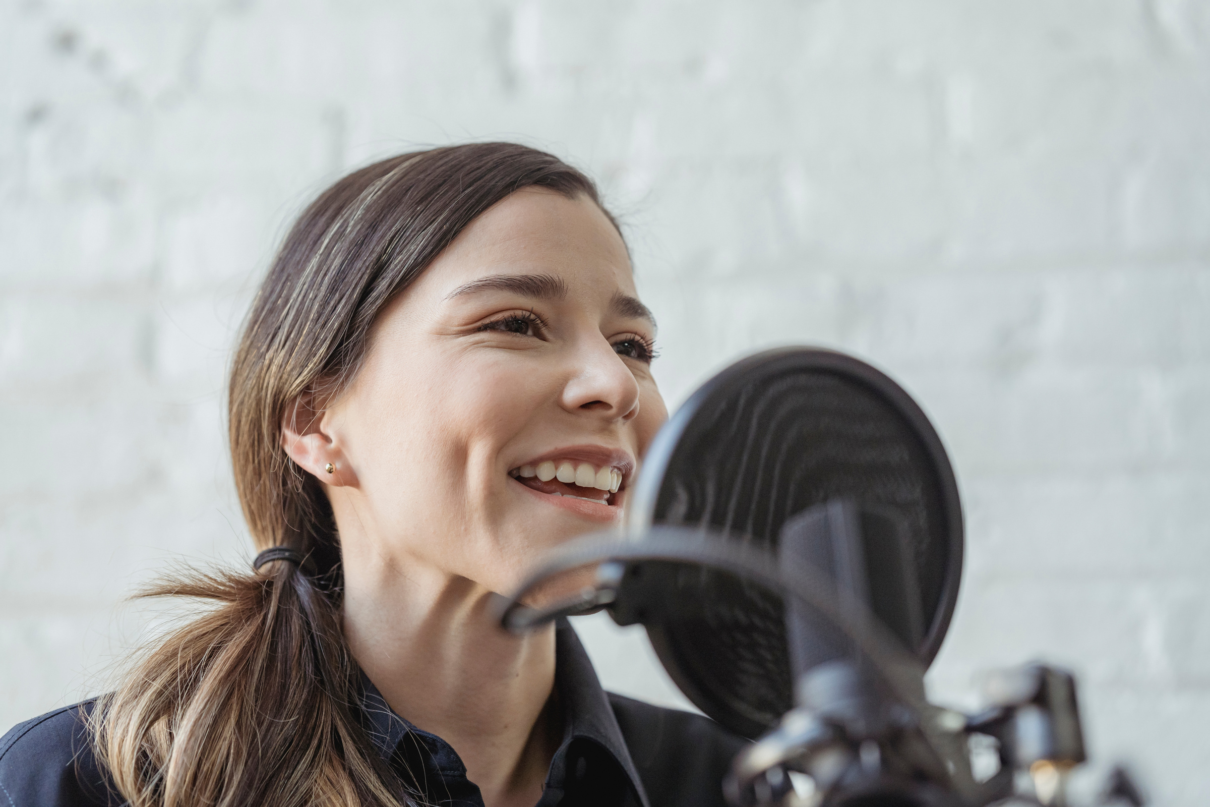 Smiling woman recording voice podcast on microphone